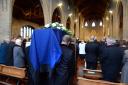 Howard Jones' coffin, draped in blue, is carried into St James Church
