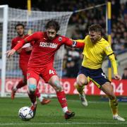 AFC Wimbledon's Alex Woodyard (left) and Oxford United's Matty Taylor battle for the ball during the Sky Bet League One match at the Kassam Stadium, Oxford.