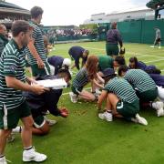 Wimbledon staff clearing up remnants of the Just Stop Oil protests on the tennis court