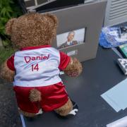 A teddy bear in an Arsenal top on a table at vigil at Hainault Underground Station Car Park, in memory of 14-year-old Daniel Anjorin