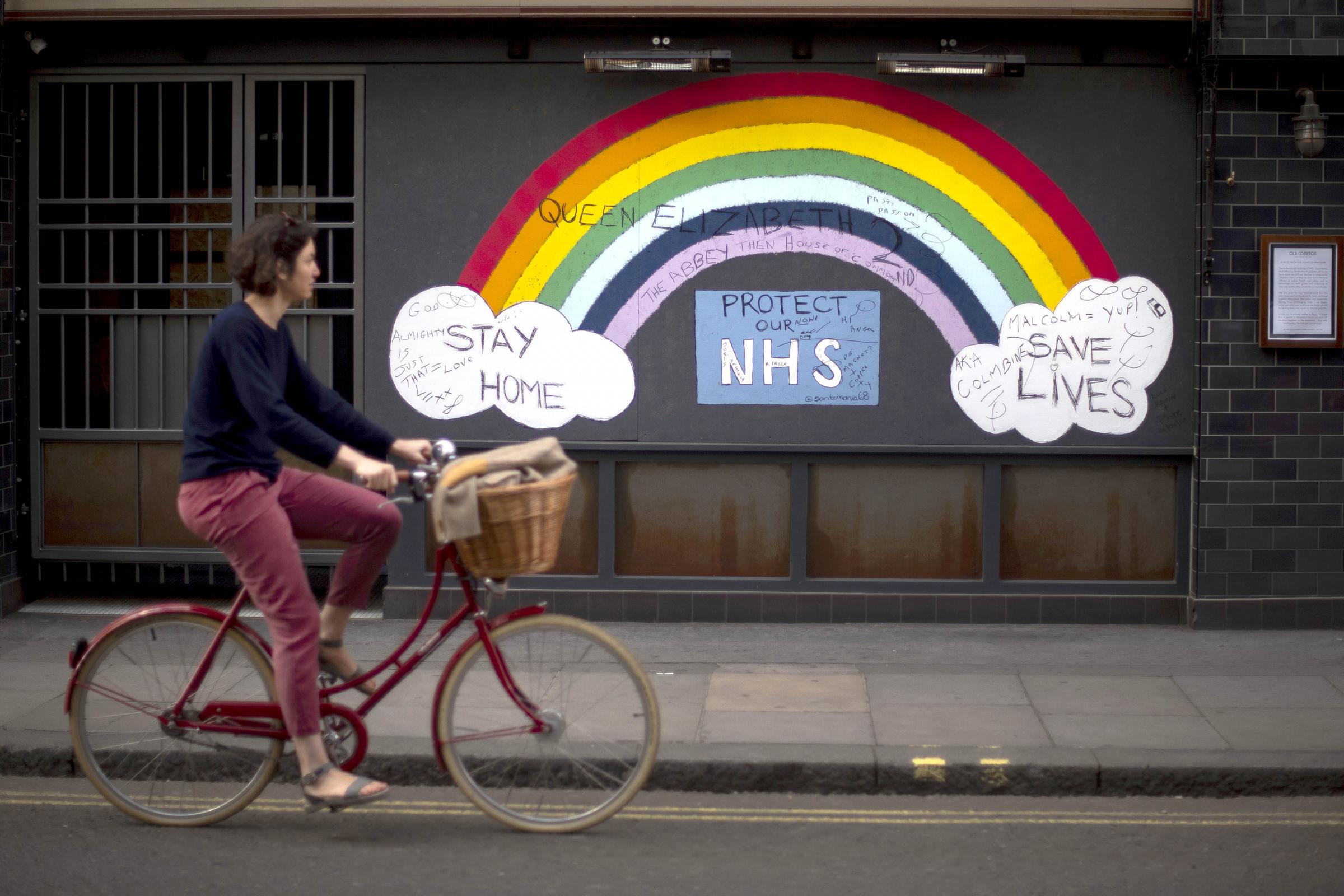 Woman cycling past a rainbow graffiti in support of the NHS in Soho, central London. Victoria Jones/PA Wire 